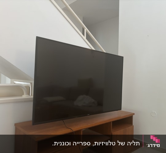 טלוויזיה מותקנת על שידה מתחת למדרגות בבית